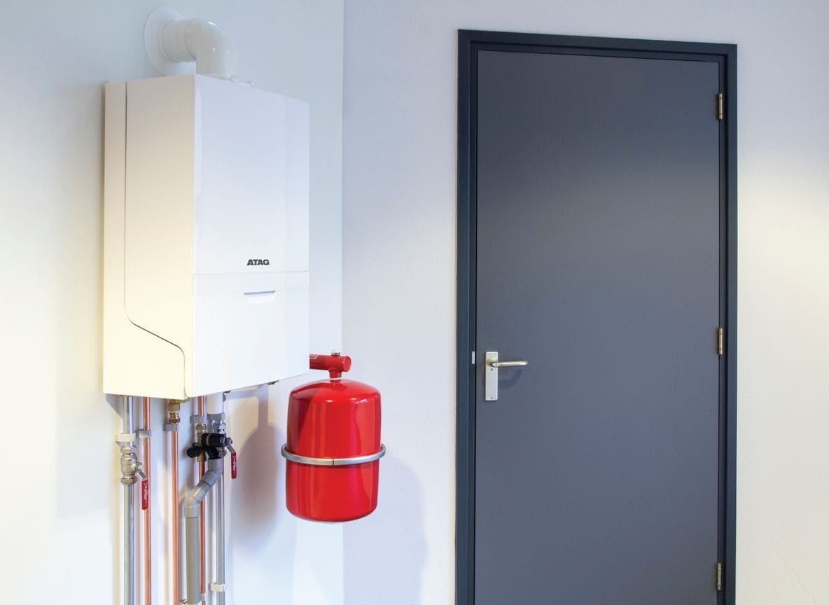 ATAG i-Serie condensatieketel met expansievat, gemonteerd naast een deur — officiële sfeerfoto van ATAG Verwarming