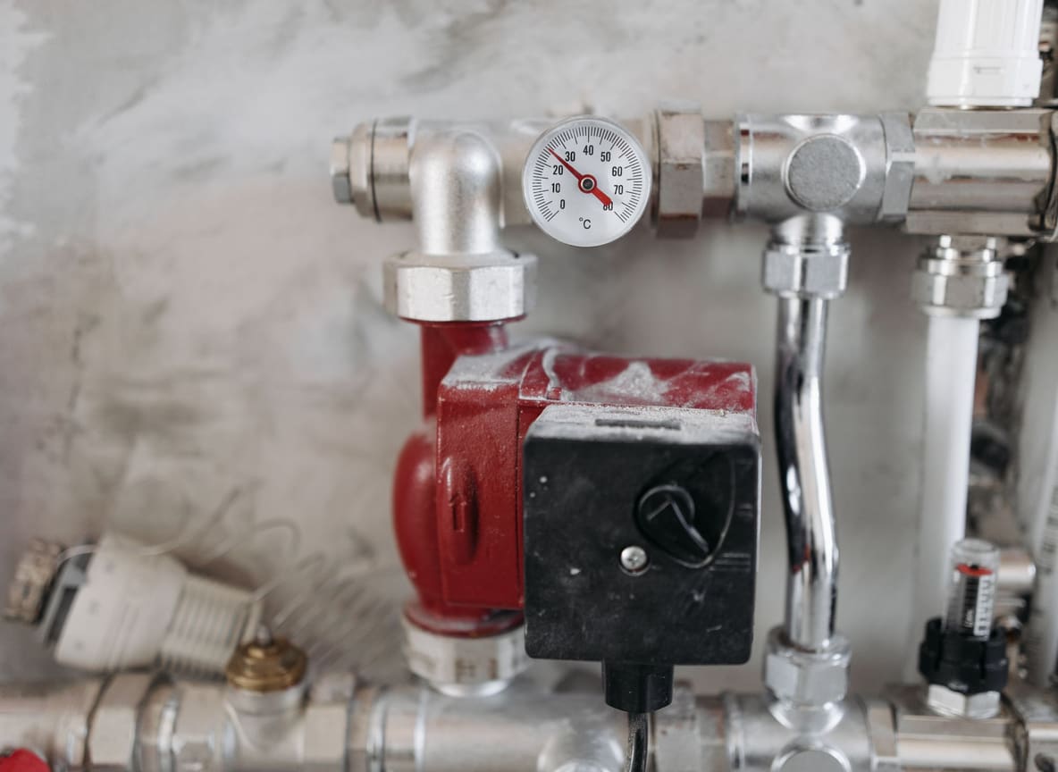 Close-up van een cv-installatie met circulatiepomp, thermometer en verzorgde leidingen